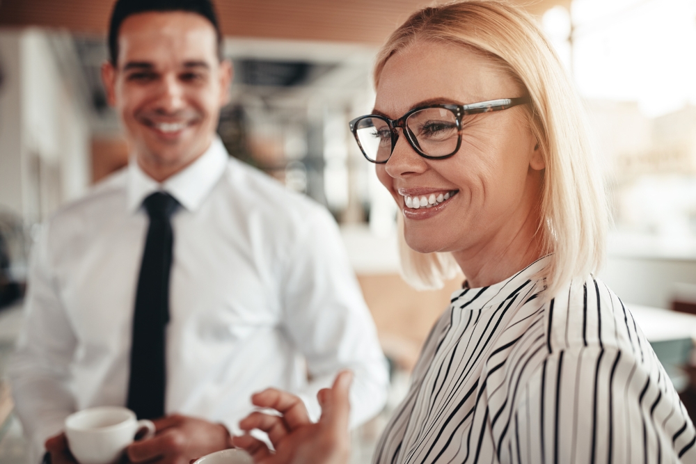 One employe in focus smiling and one employee out of focus smiling