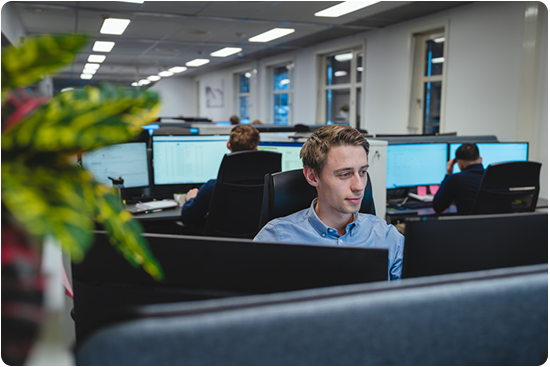 Ansatt jobber på pc i åpent kontorlandskap