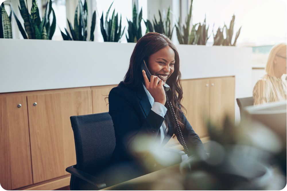 Woman smiling talking on the phone at a desk