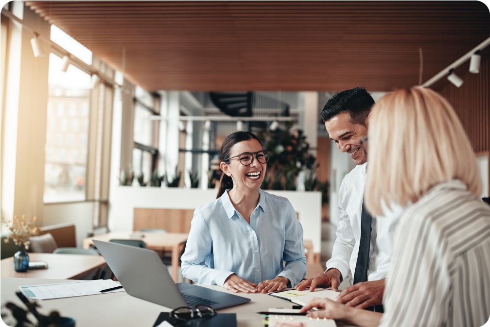 Three employees smiling and laughing at the office