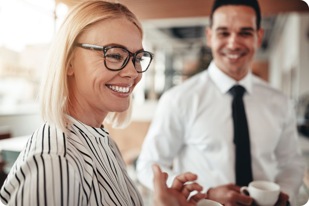 Two business people smiling, one blurred